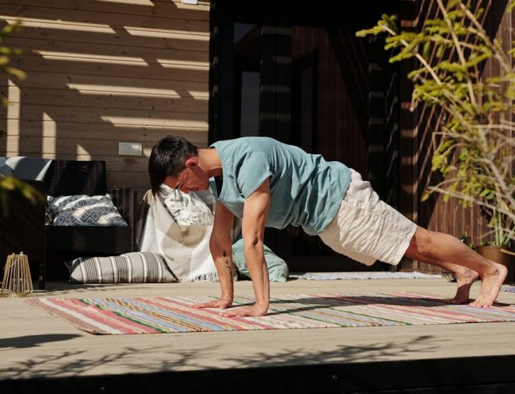Adult man doing a plank exercise on a colorful yoga mat outdoors, promoting fitness and healthy living.
