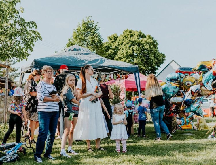 A lively outdoor gathering with families enjoying balloons and a sunny day.