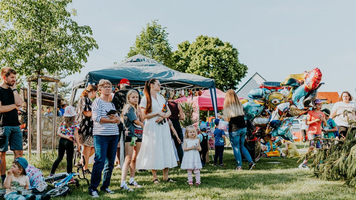 A lively outdoor gathering with families enjoying balloons and a sunny day.